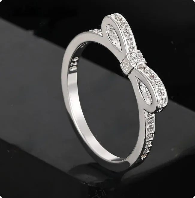 Silver couple ring with a bow shape set with rhinestones and zircon crystals.