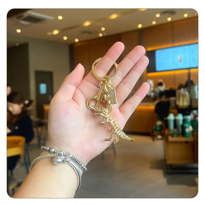 Golden bone dragon zinc alloy dinosaur keychain on a neutral background, showing retro animal pattern