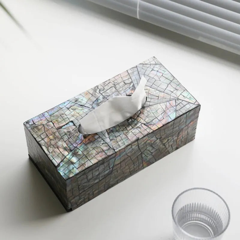 A black rectangular shell tissue box holder with a removable lid on a wooden coffee table.