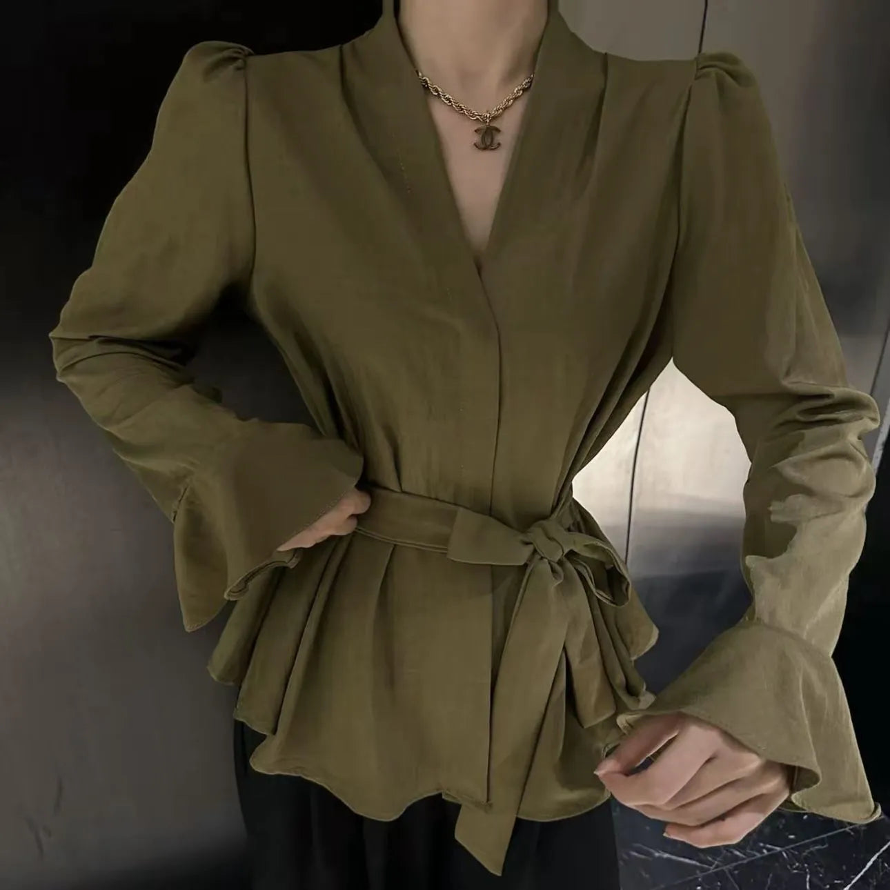 Women's black French-style shirt with an irregular collar and long bell sleeves laid flat.