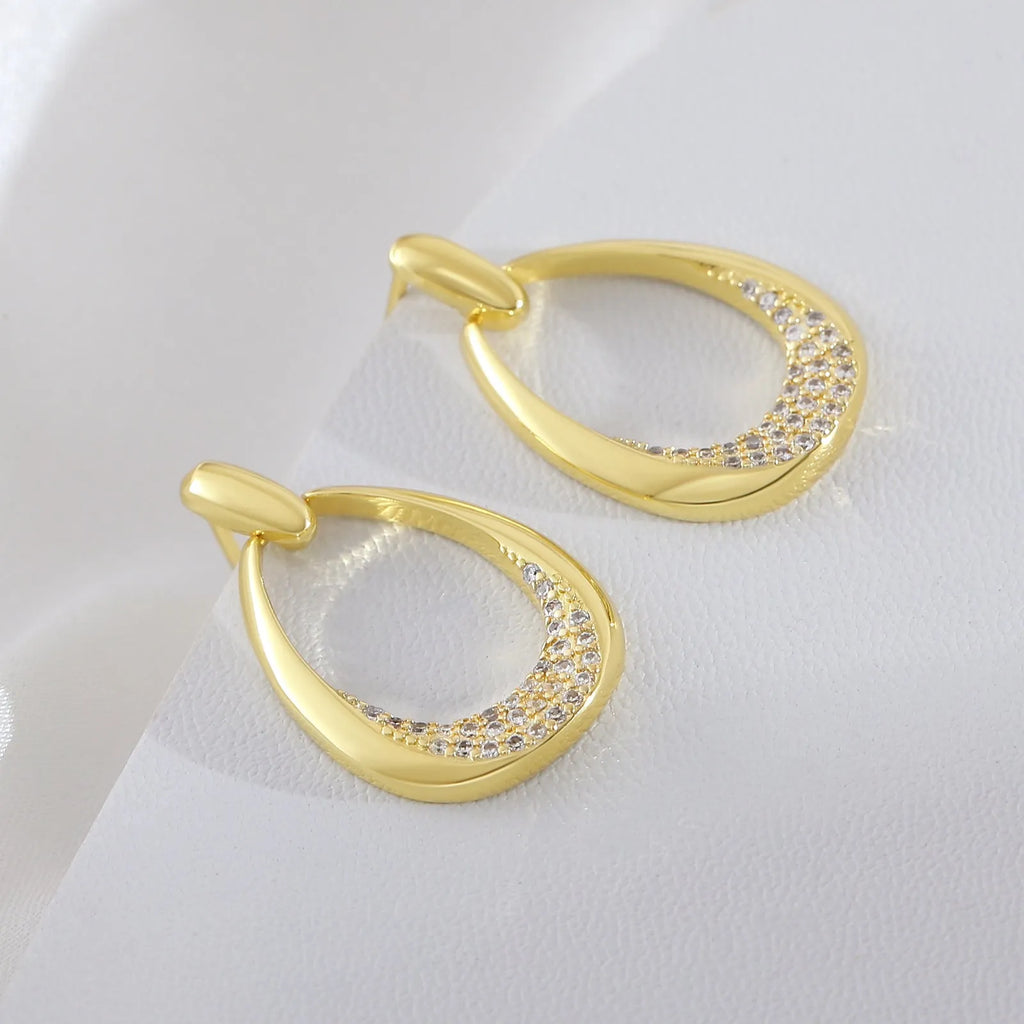 Yellow gold geometric drop-shaped women's earrings with round and oval ring elements on a simple background.