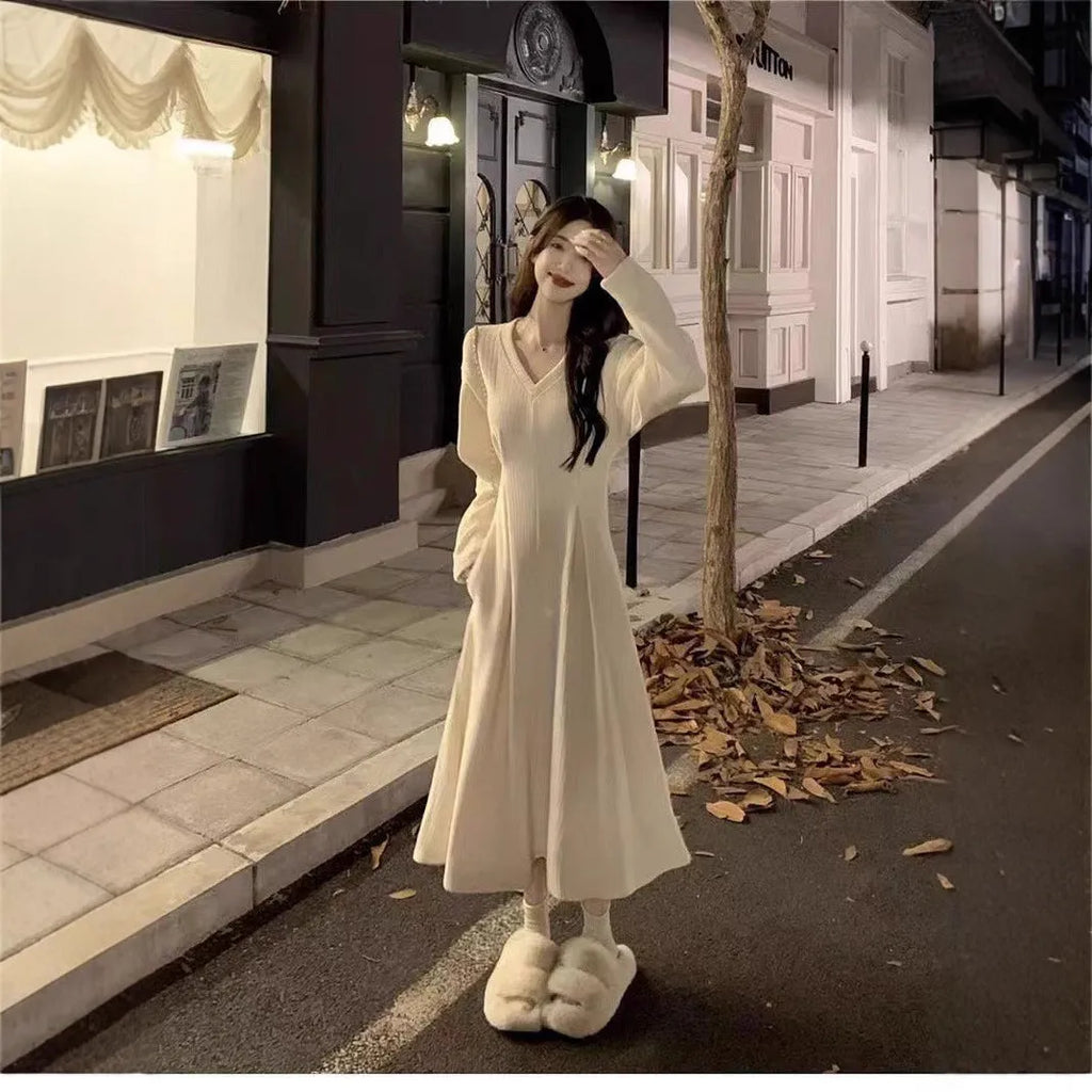 Women's milky white V-neck knitted long dress with princess sleeves on a hanger.