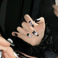 Black and pink heart pattern press-on nails with hand-painted bow decoration in cat's eye finish