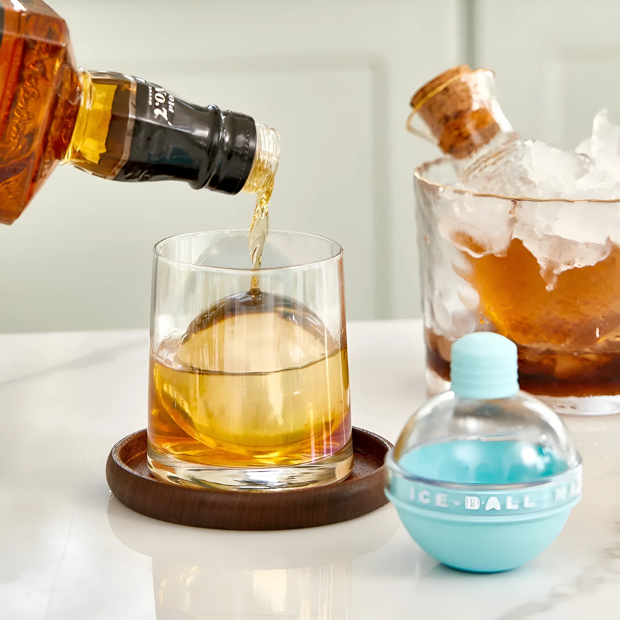 Blue spherical silicone ice ball mold producing a 6cm clear ice ball for whiskey, on a wooden table