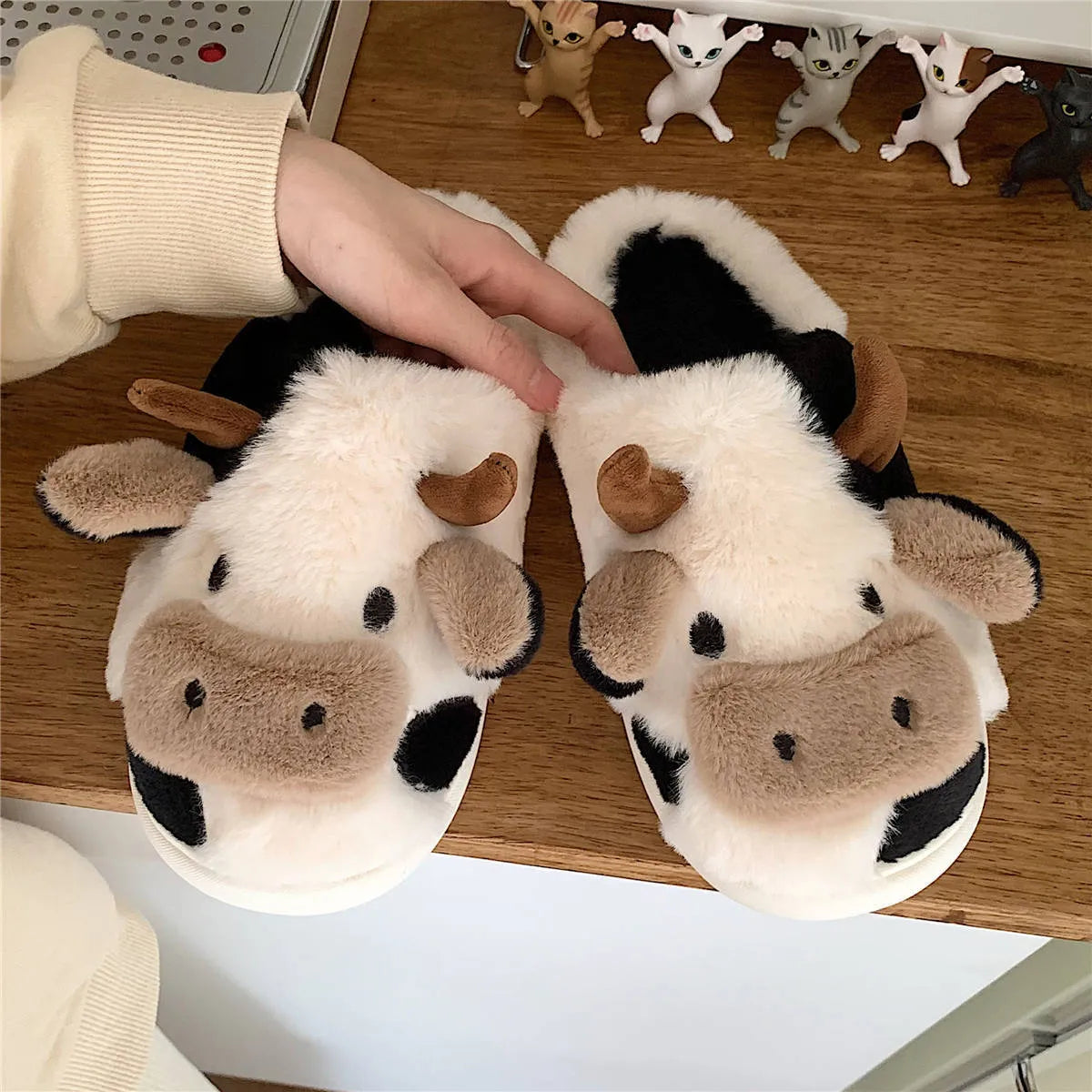 White cow-themed faux fur slippers with black spots and a textured grey anti-slip sole.