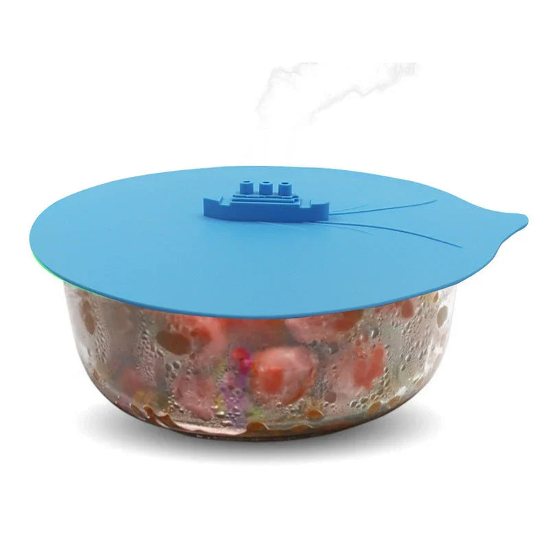 A silicone cooking lid with a ship-inspired design, featuring a three-port steam release system and a convenient hook for easy storage.