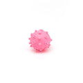 Set of bright blue, green, pink, and yellow spiked squeaky dog balls for small dogs on a lawn.