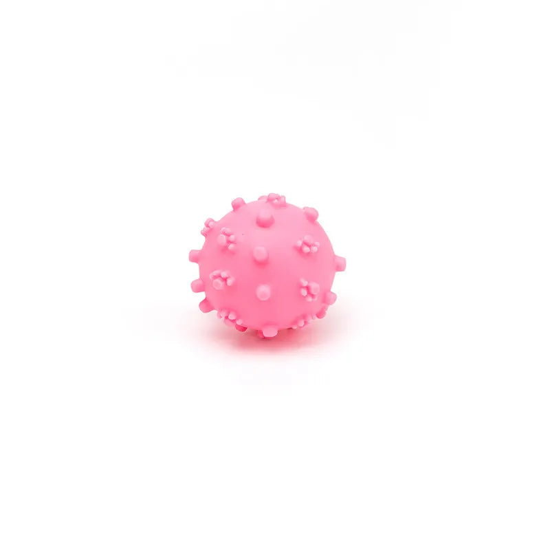 Set of bright blue, green, pink, and yellow spiked squeaky dog balls for small dogs on a lawn.