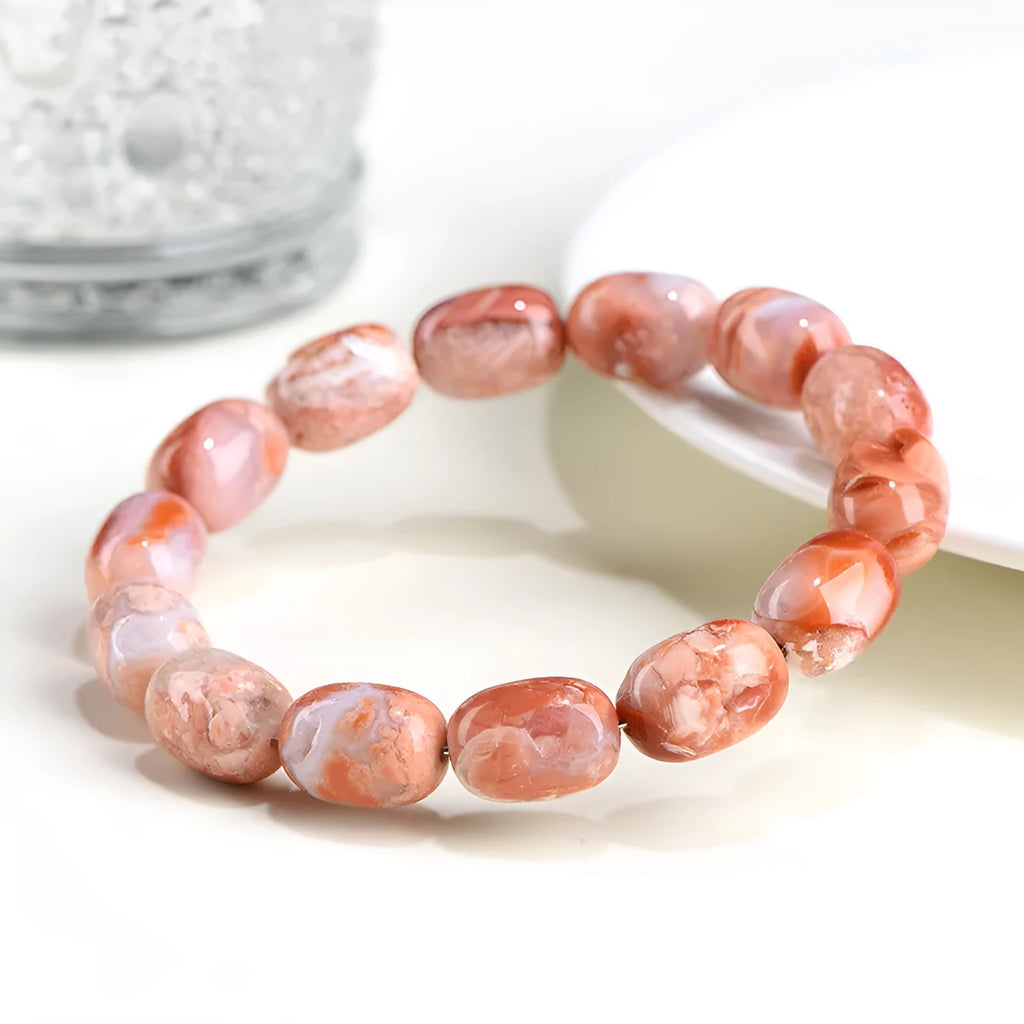 Natural cherry agate barrel bead bracelet with Ruyi charm on a white background.