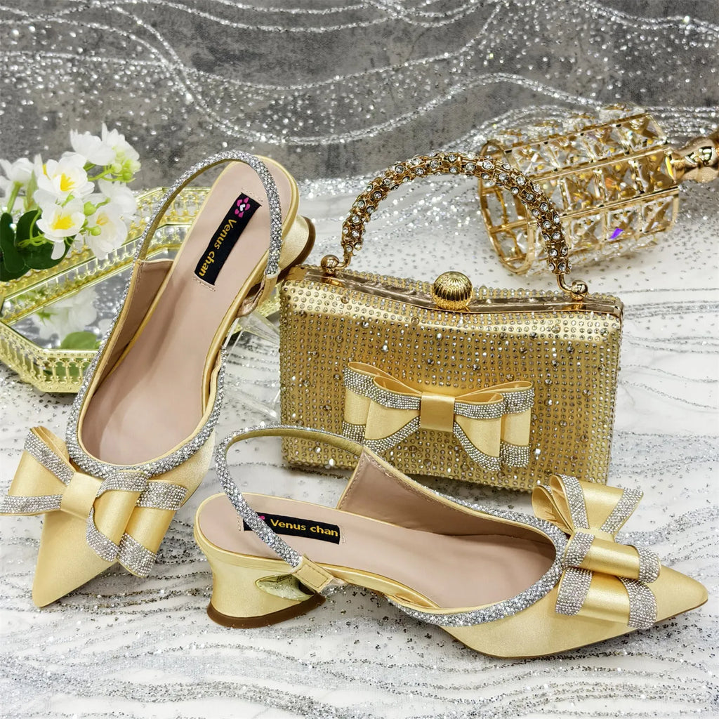Women's black pointed toe sandals with elastic band and matching square rhinestone clutch bag on a neutral background.