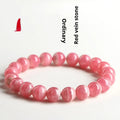 Women's red rhodochrosite crystal bracelet with geometric beads and longevity lock charm on wrist