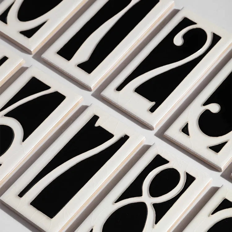 Handmade ceramic retro doorplate with enamel art number on a dark background.