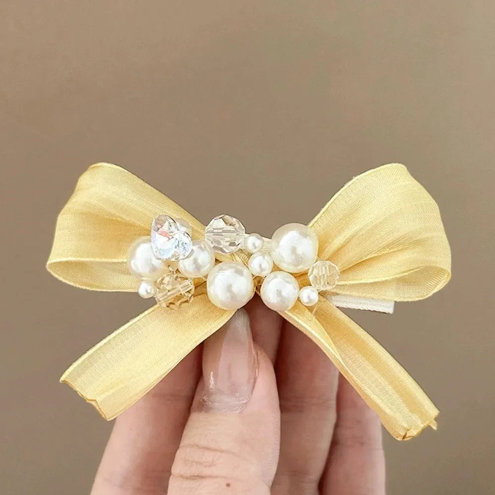 Yellow bow hair barrette with rhinestone pearl detailing and duckbill clip design