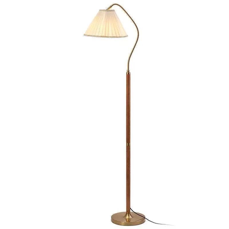 Solid wood floor lamp with fabric shade in walnut colour placed beside a sofa in a living room