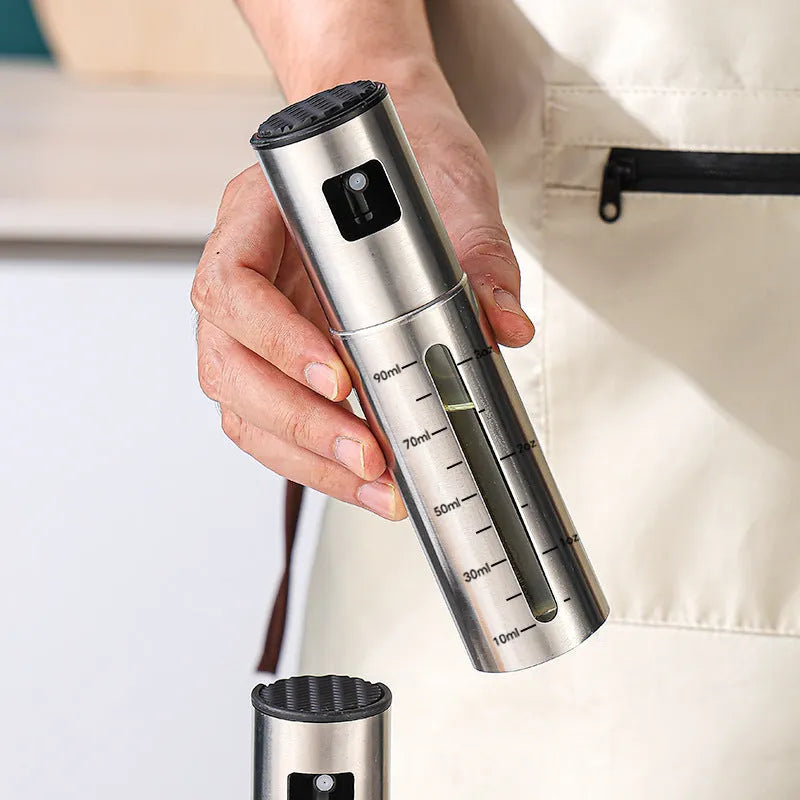 Stainless steel press-type oil injection bottle with 100ml capacity and glass body on kitchen counter