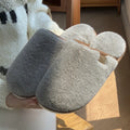 Blue plush slipper with non-slip PVC sole and car-stitching detail on a wooden floor.