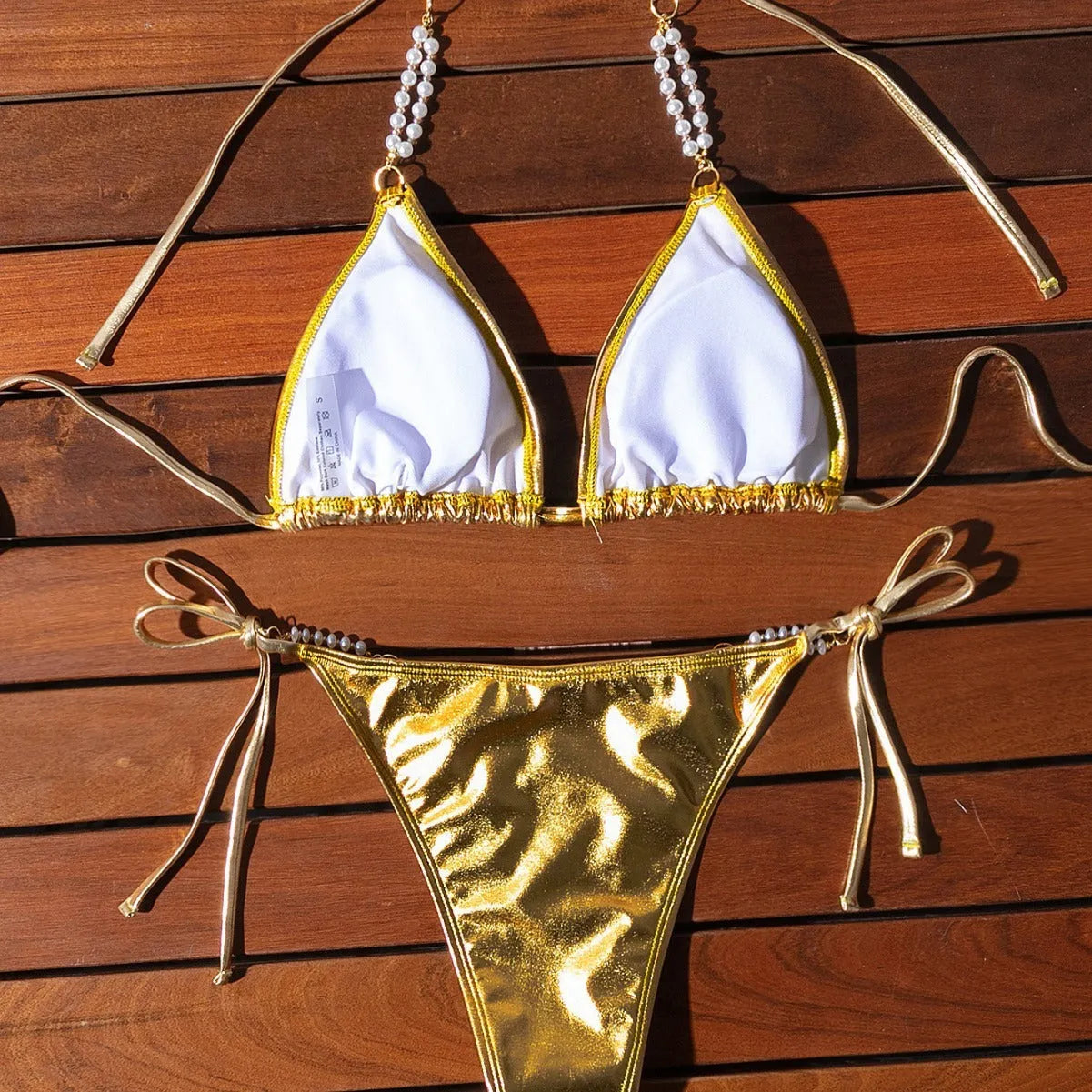 Gold women's bikini swimsuit with halter neck, lace-up back, and pearl chain decoration
