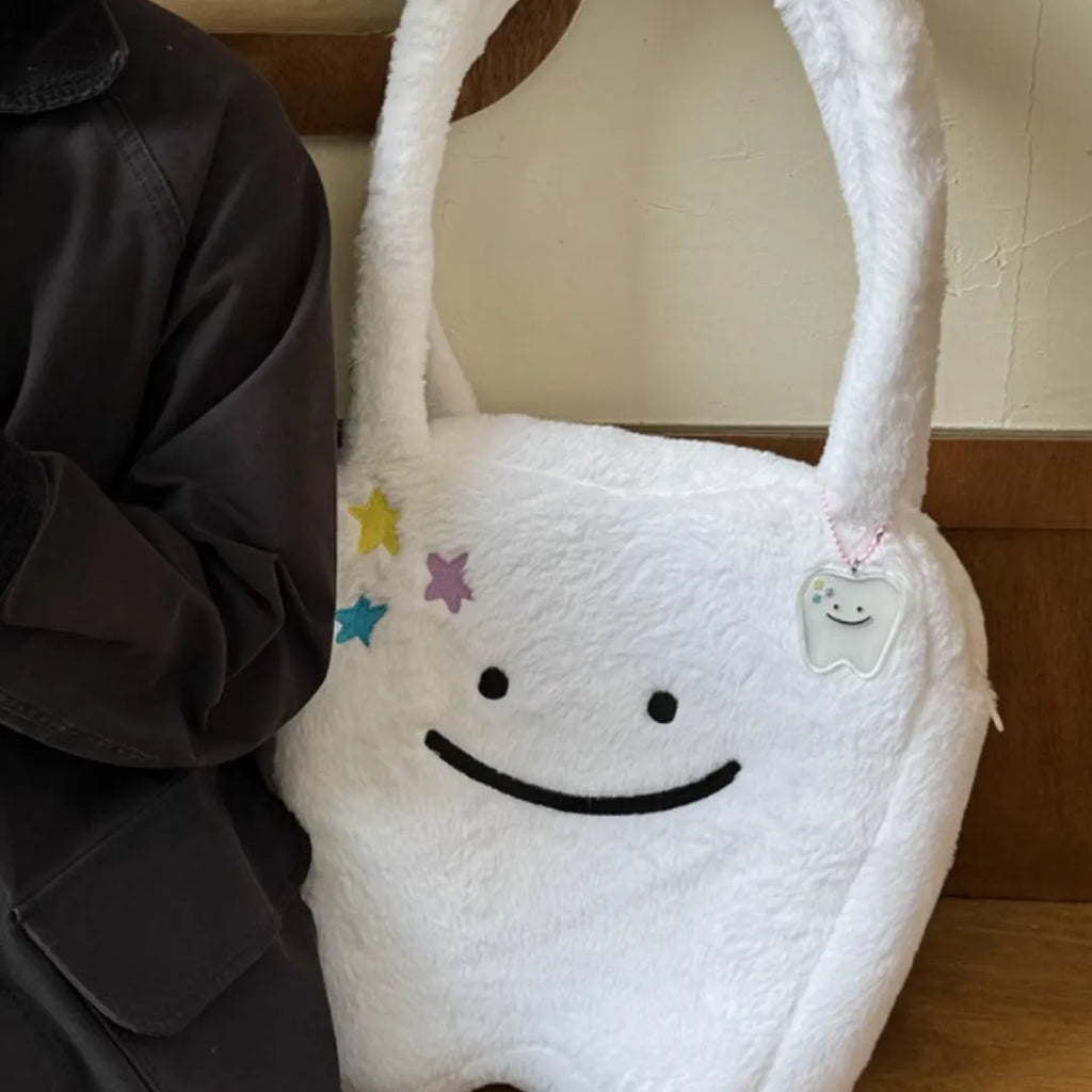 White plush tote bag with a cute teeth graphic, showing the crossbody strap and zipper opening.