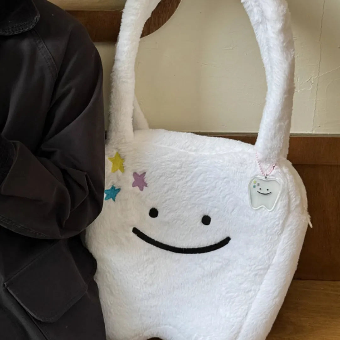 White plush tote bag with a cute teeth graphic, showing the crossbody strap and zipper opening.