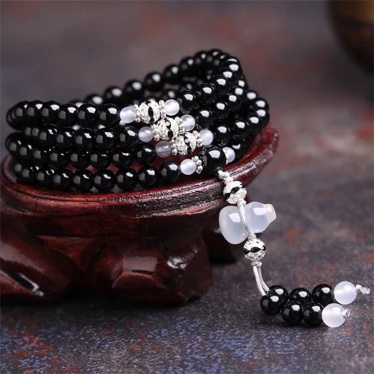 Natural black agate 108 bead bracelet with 8mm geometric beads on a wrist.