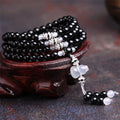 Natural black agate 108 bead bracelet with 8mm geometric beads on a wrist.