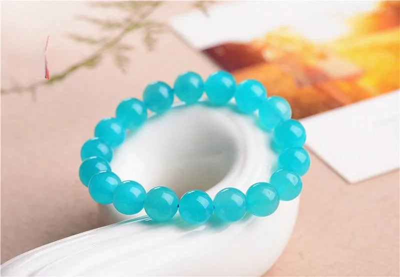 Natural blue-green Amazonite scattered loose beads in various sizes next to a finished crystal bracelet.