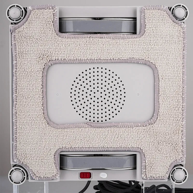 White square window cleaning robot with water spray nozzles on a glass window pane.