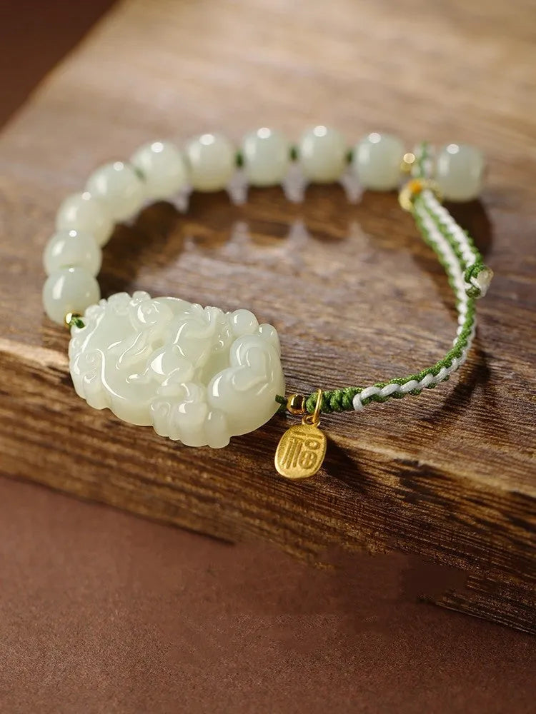 Year of the Rabbit red cord bracelet with Hetian jade charm and small silver blessing card.