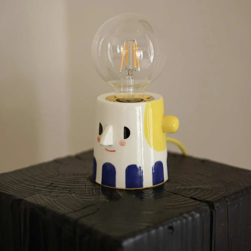 Handmade ceramic bedside lamp with a creative ball headlight design on a wooden table.