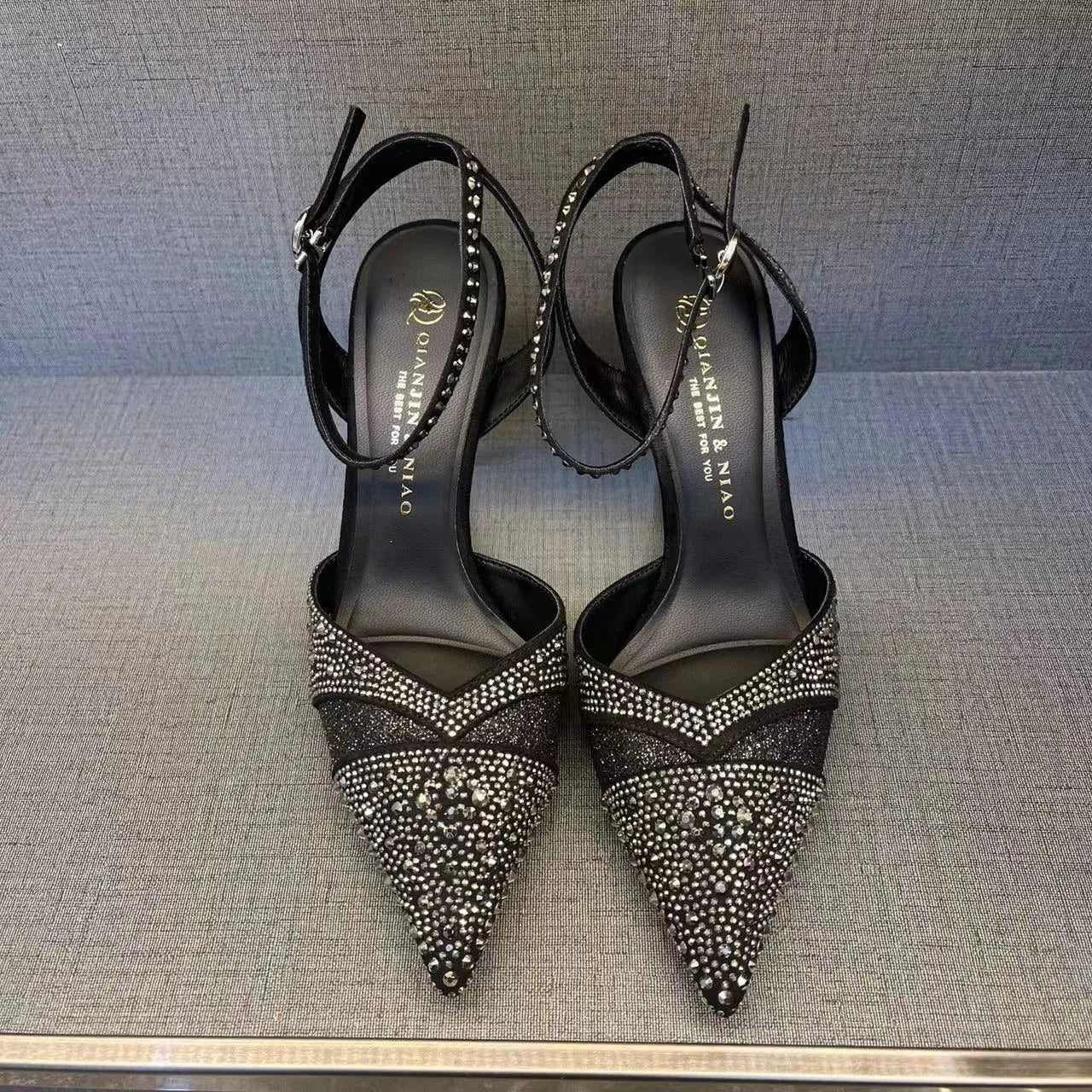 Women's black hollow stiletto heel pump shoe with pointed toe and red sole on a white background.