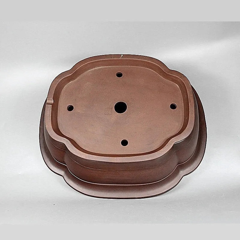 Handmade antique crabapple shaped large purple clay flowerpot on a floor.