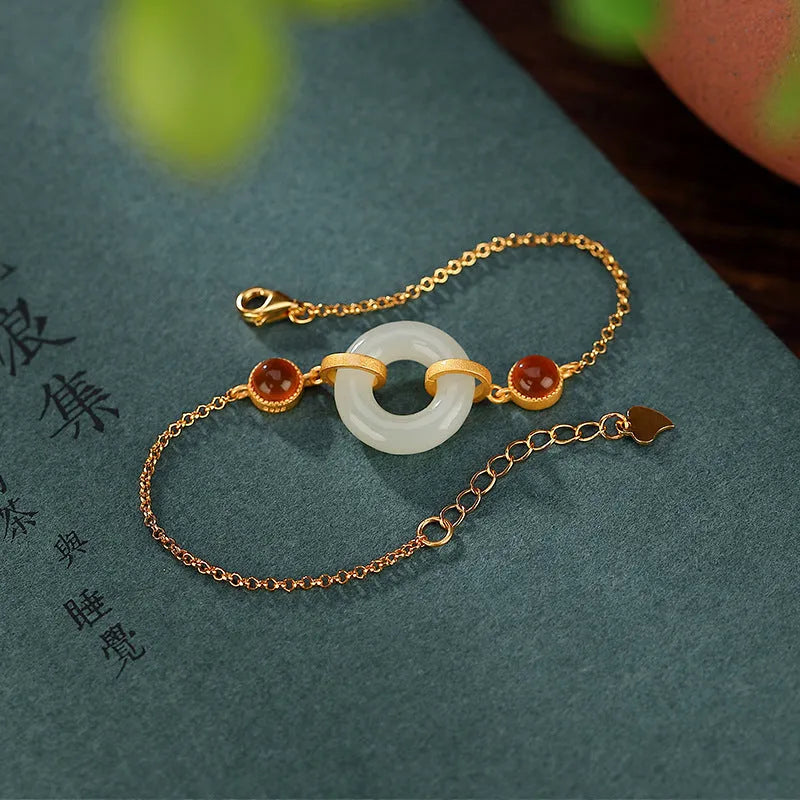 Gold-coloured women's bracelet with a sterling silver base and an inlaid natural Hetian jade peace symbol buckle.