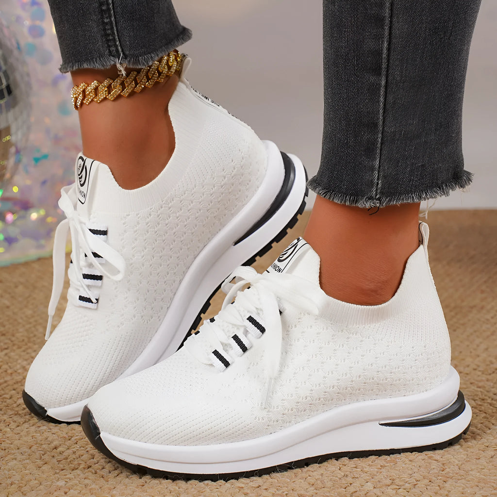 Women's black and white lace-up sneakers with mesh upper and flat rubber sole on a white background.