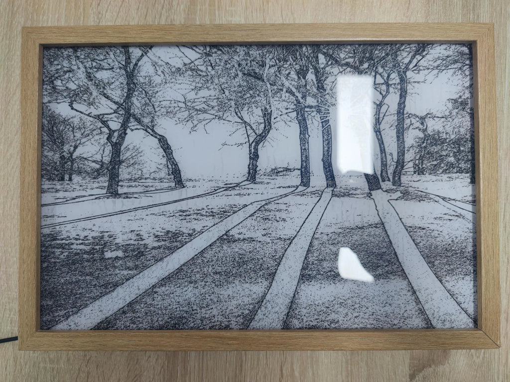 Illuminated LED decorative picture frame showing a scenic print with soft backlighting, featuring a wooden frame and a button switch.