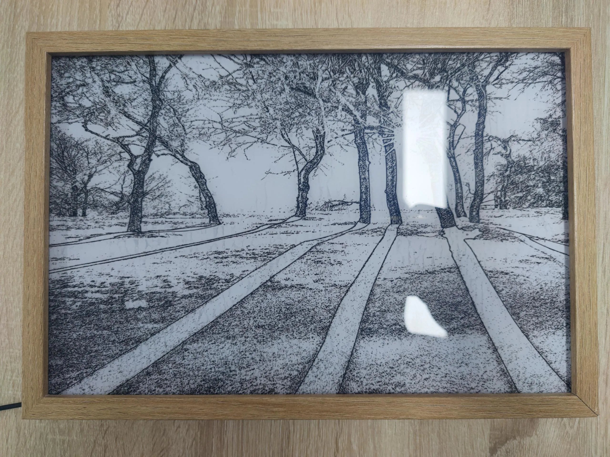 Illuminated LED decorative picture frame showing a scenic print with soft backlighting, featuring a wooden frame and a button switch.
