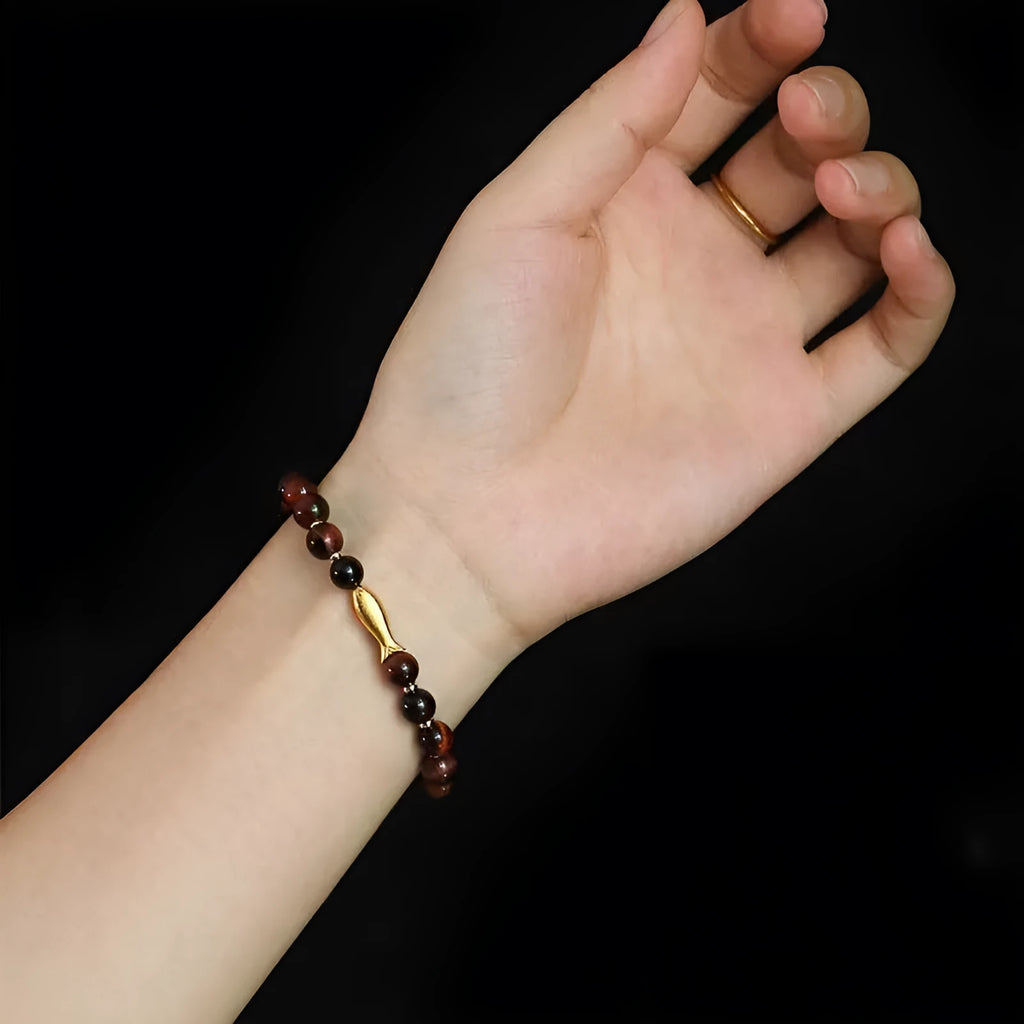 Women's tiger eye bracelet with small gold fish charm on adjustable band