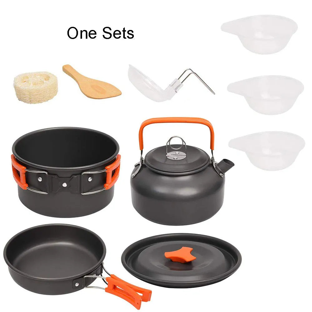 Orange folding camping cookware set with pots, pan, spoons, bowls in mesh bag on outdoor table