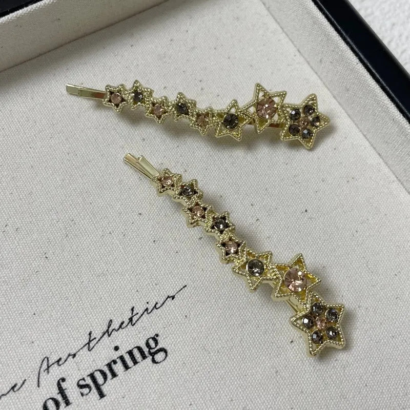Gold alloy rhinestone barrette with a side clip, star decoration, and text.