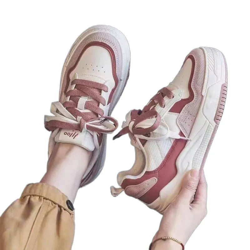 Pink and white low top women's sneakers with a rubber sole and height increasing feature.