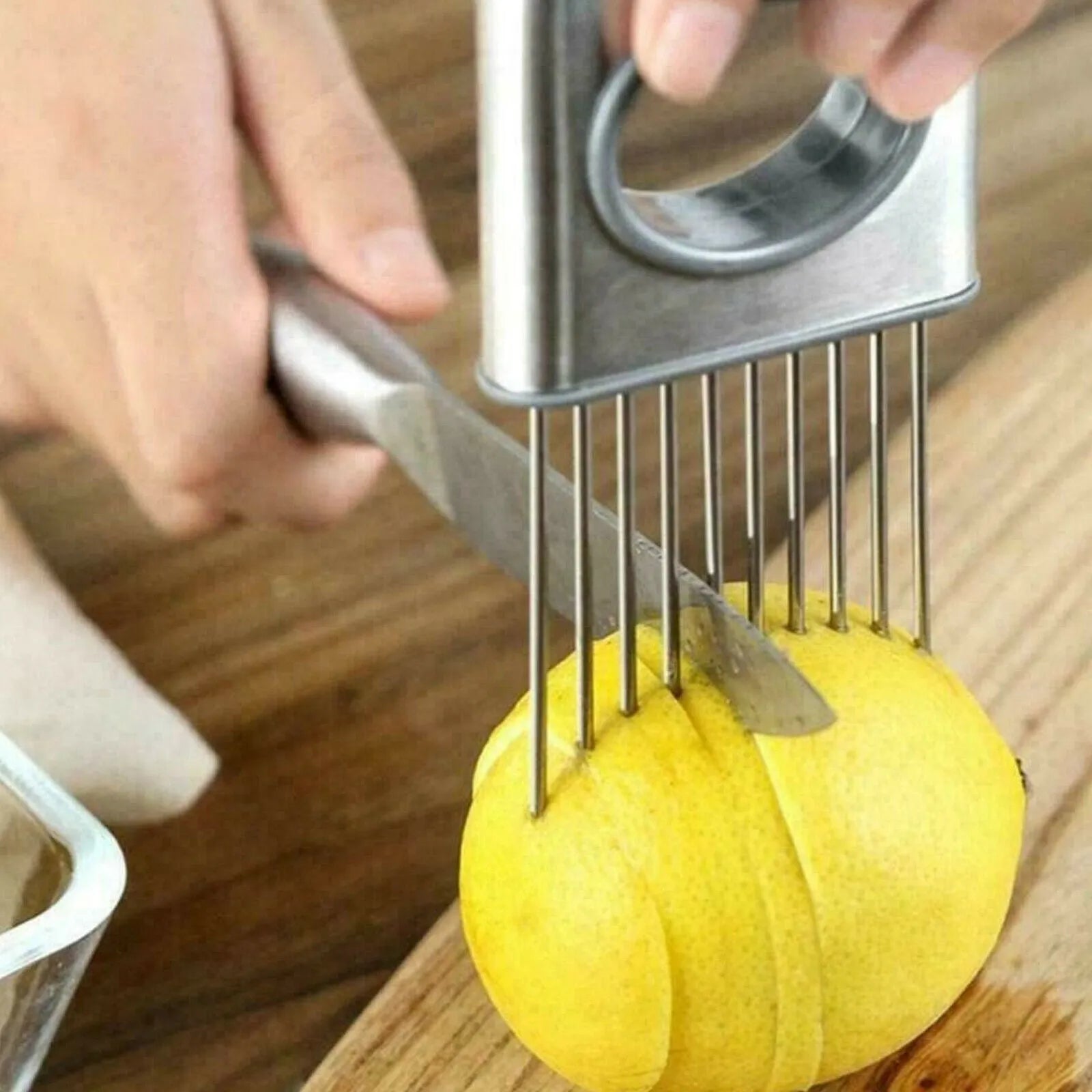 Stainless steel onion holder with sharp prongs and a finger guard on a kitchen counter.