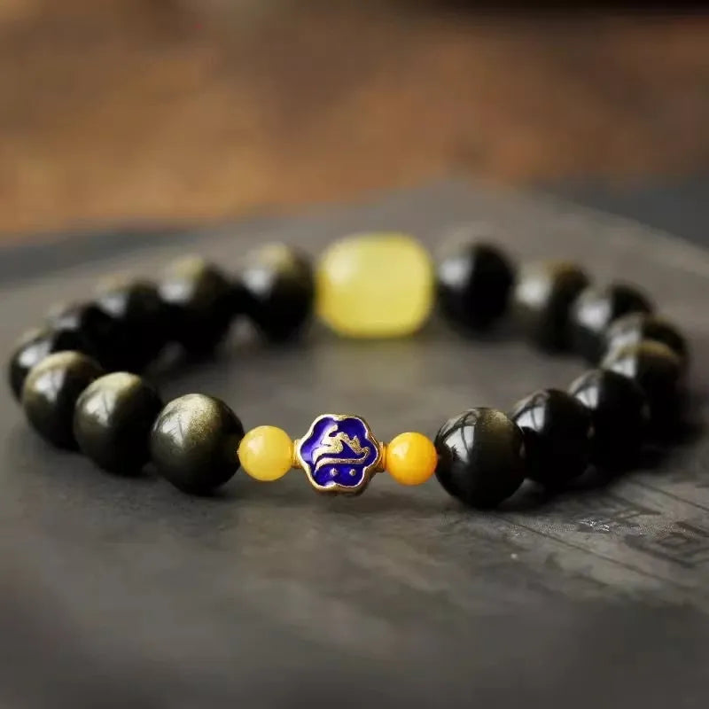 Golden obsidian bracelet with carved zodiac symbols on geometric beads