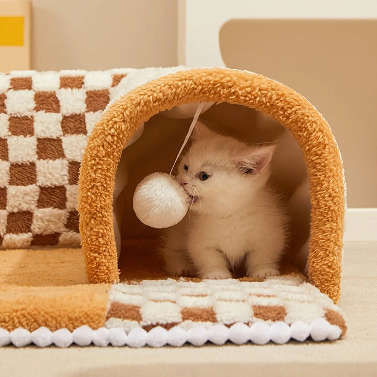 Large plush fan-shaped dog and cat bed with central tunnel, in coffee colour, on a floor.