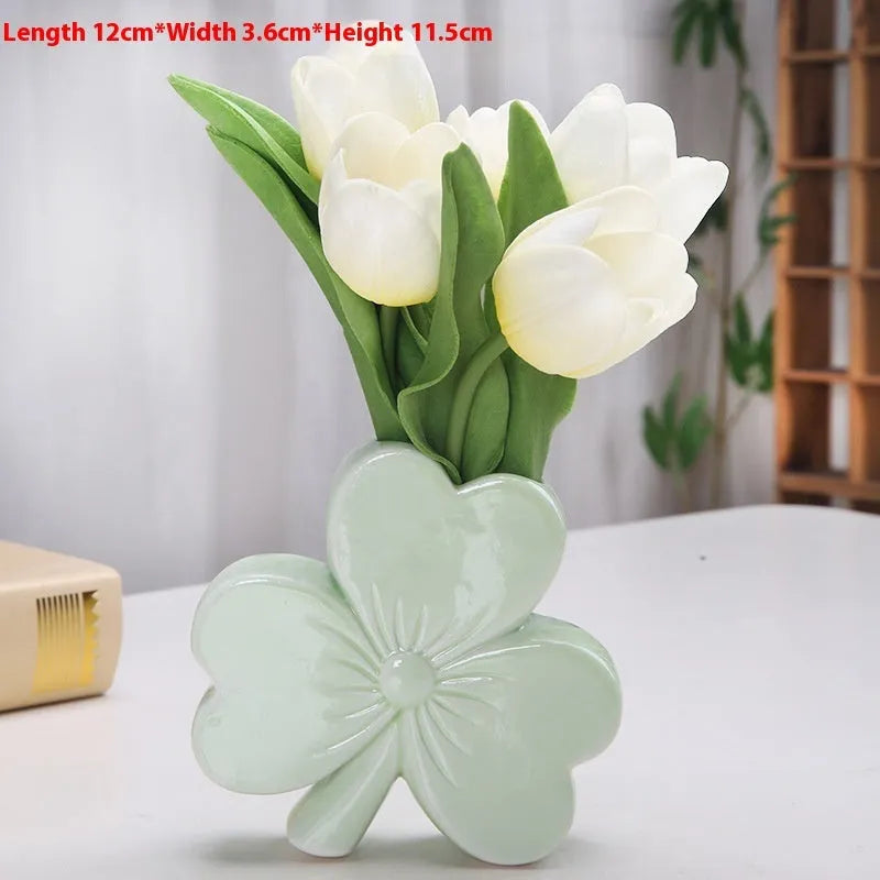 Small clover-design ceramic vase in pink, red, light green, or white on a desktop.