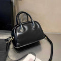 Genuine leather mini bowling bag in pillow shape with top grain finish and inner pockets.