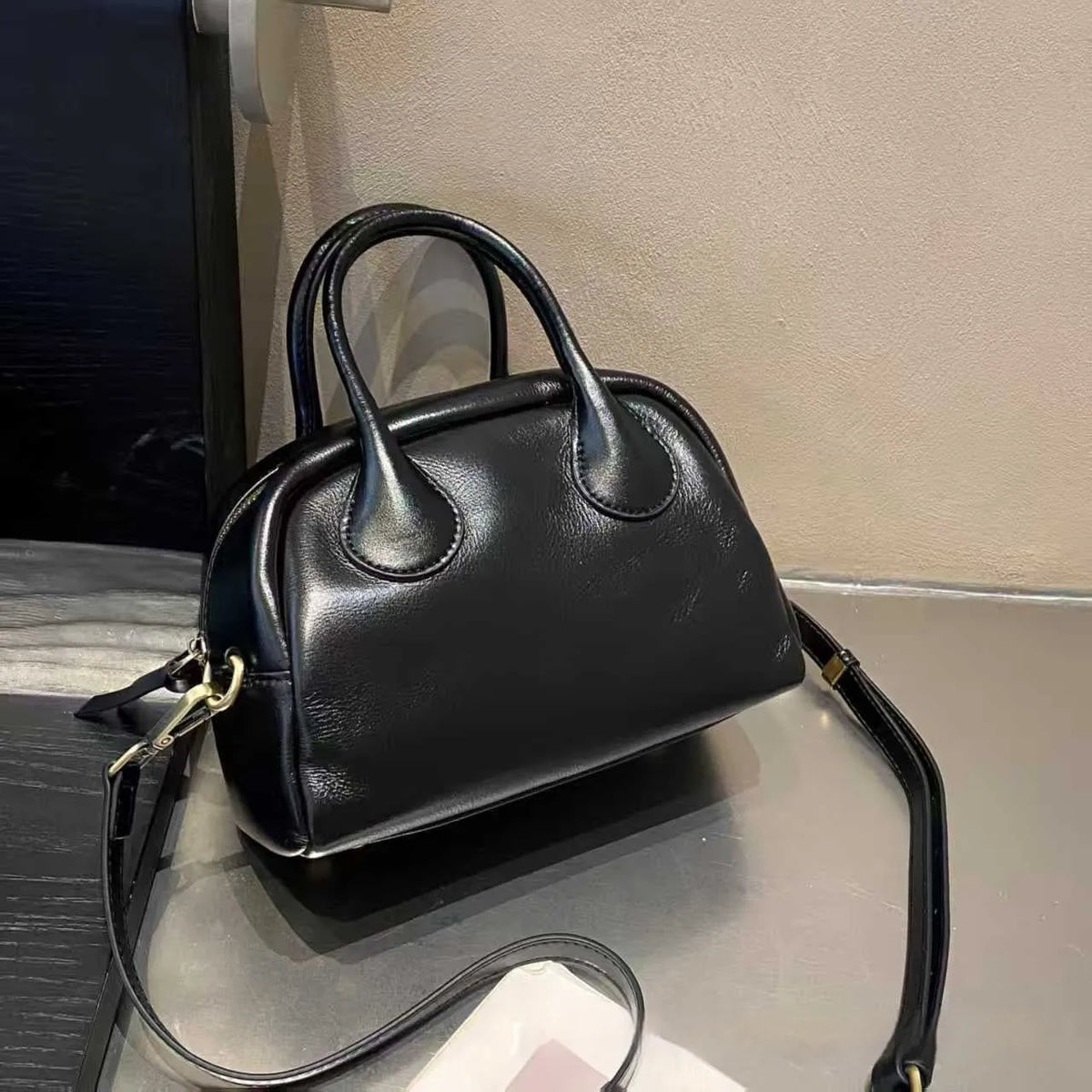 Genuine leather mini bowling bag in pillow shape with top grain finish and inner pockets.