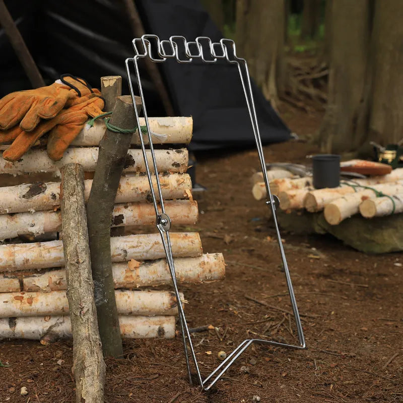 Silver folding stainless steel garbage bag holder bracket on a wooden surface.