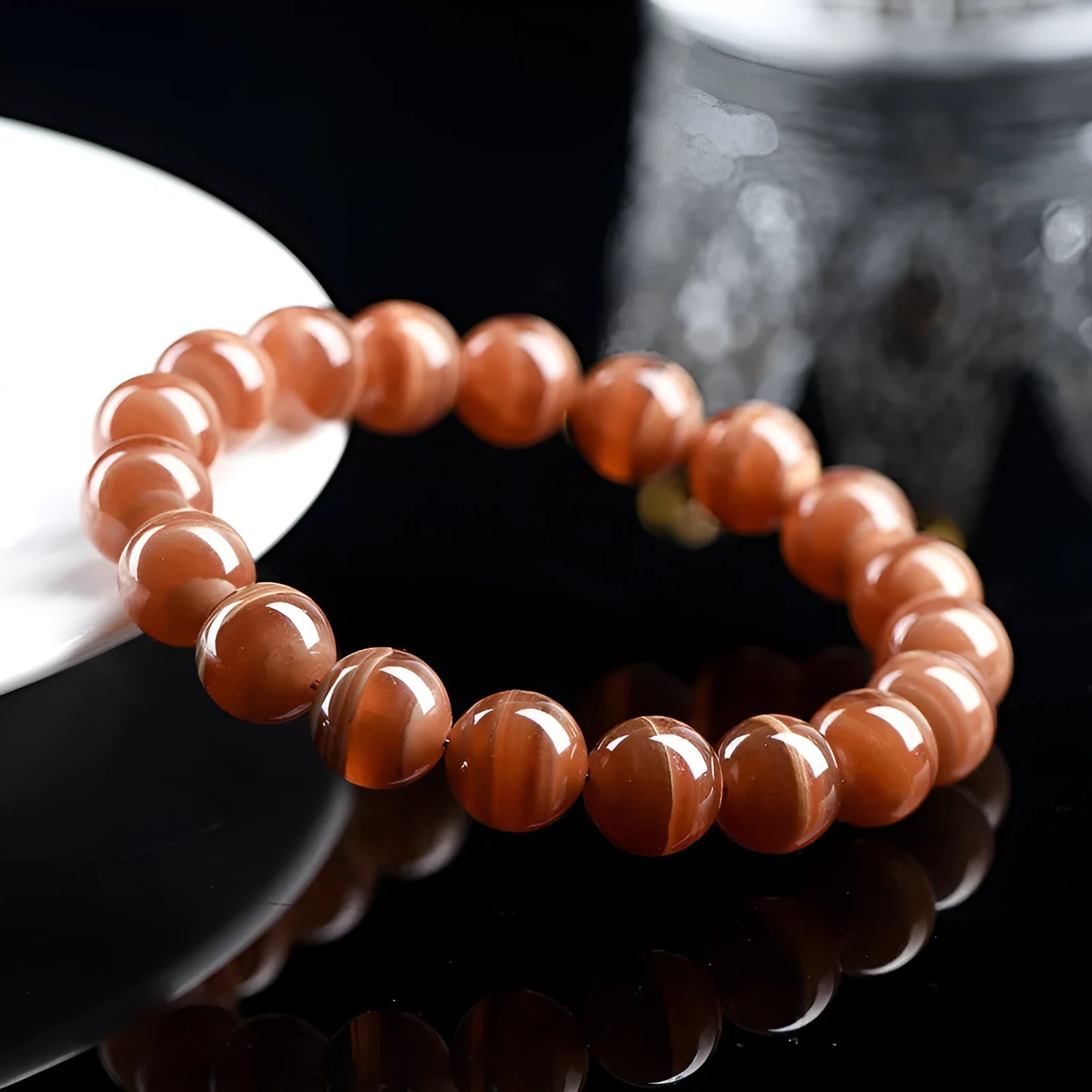 Natural old mine rhodochrosite round bead bracelet on wrist, showing geometric design and Ruyi symbol.