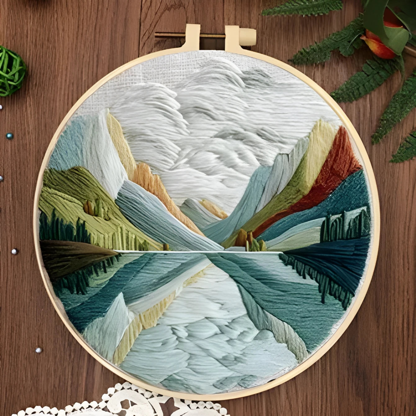 Complete DIY embroidery kit showing pre-printed landscape fabric, coloured threads, needles, and an embroidery frame.