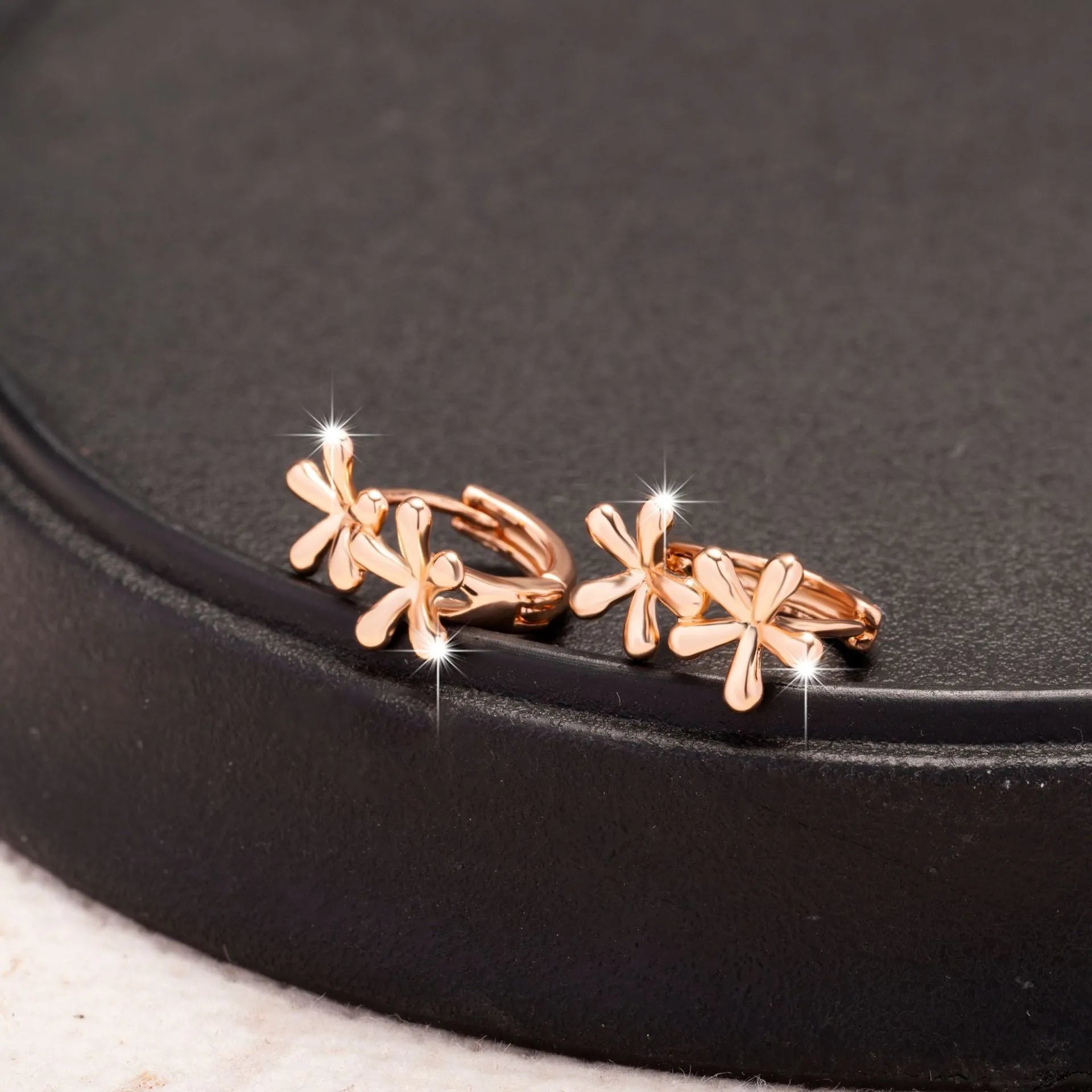 Rose gold circular earrings with a waterdrop flower design.