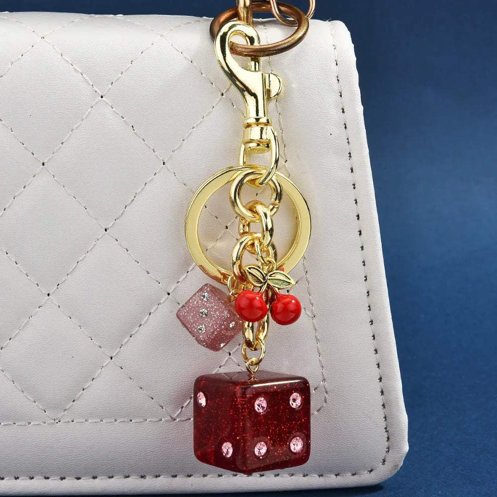 Square metal keychain pendant with a vintage two-tone cherry dice pattern.